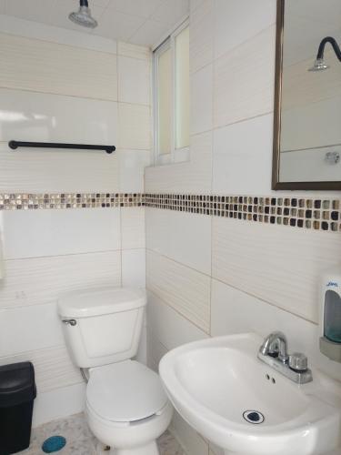 a white bathroom with a toilet and a sink at Hotel Business in El Gallinero