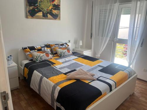 a bedroom with a bed with a colorful blanket at Paloma Caparica Beach in Costa da Caparica
