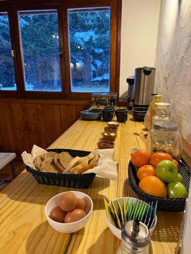 a table with baskets of fruit and bread on it at Nevada Hostel in San Carlos de Bariloche