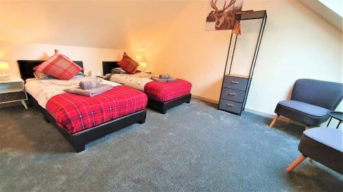 a bedroom with two beds and a chair and a mirror at Birchbank House in Roybridge