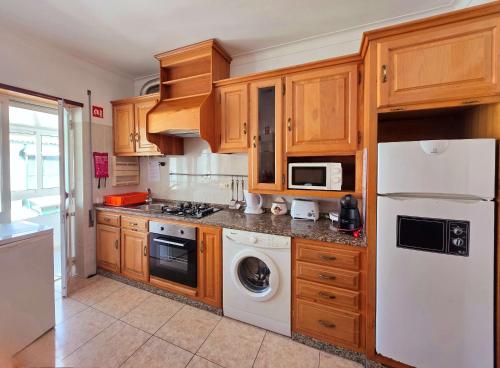 a kitchen with wooden cabinets and a white refrigerator at Novas Direcões in Melgaço