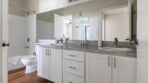 a white bathroom with two sinks and a toilet at Landing at Champions Walk - Longboat Key in Longboat Key