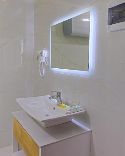a white bathroom with a sink and a mirror at Анис in Khujand