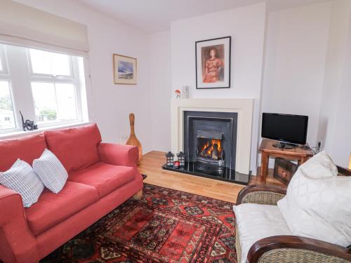 a living room with a red couch and a fireplace at The Burma in Letterkenny
