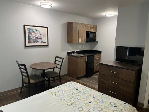 a small room with a bed and a kitchen with a table at HomeTowne Studios & Suites by Red Roof Charlotte - Ballantyne in Charlotte