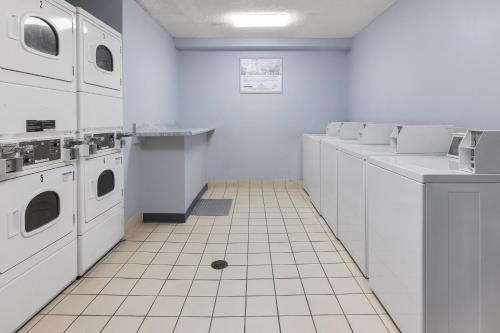 a white laundry room with a drain in the floor at HomeTowne Studios & Suites by Red Roof Charlotte - Ballantyne in Charlotte