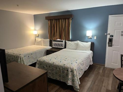 a hotel room with two beds and a table at HomeTowne Studios & Suites by Red Roof Charlotte - Ballantyne in Charlotte