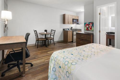 a hotel room with a bed and a desk and a kitchen at HomeTowne Studios & Suites by Red Roof Charlotte - Ballantyne in Charlotte