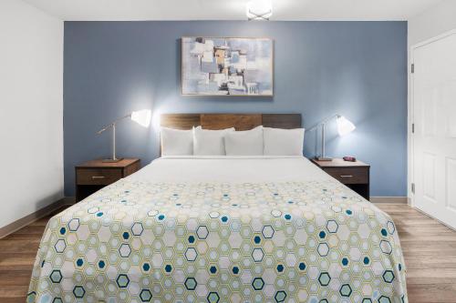 a bedroom with a large bed with two night stands at HomeTowne Studios & Suites by Red Roof Charlotte - Ballantyne in Charlotte