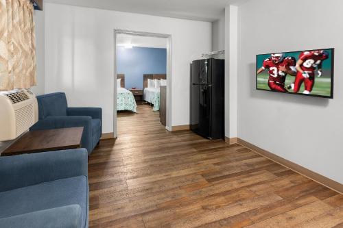 a living room with a couch and a tv on a wall at HomeTowne Studios & Suites by Red Roof Charlotte - Ballantyne in Charlotte