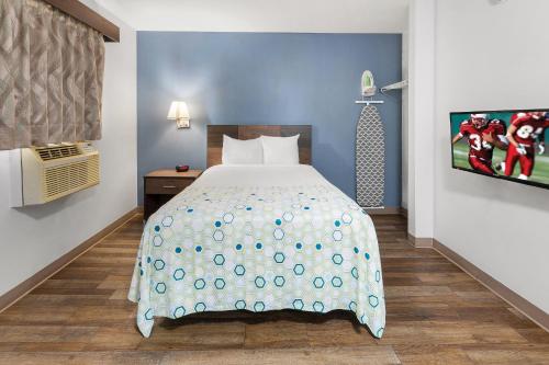 a bedroom with a bed and a tv on a wall at HomeTowne Studios & Suites by Red Roof Charlotte - Ballantyne in Charlotte
