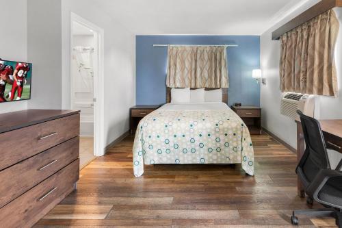 a bedroom with a bed and a dresser and a desk at HomeTowne Studios & Suites by Red Roof Charlotte - Ballantyne in Charlotte