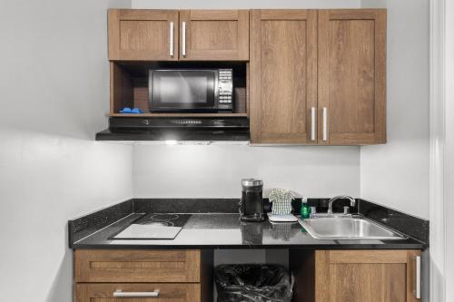 a kitchen with a sink and a microwave at HomeTowne Studios & Suites by Red Roof Charlotte - Ballantyne in Charlotte
