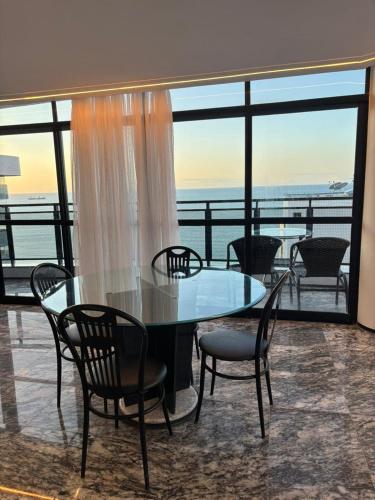 a glass table and chairs with a view of the ocean at Hotel Brasil Tropical in Fortaleza