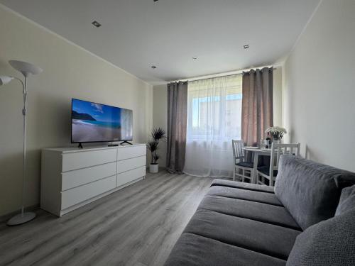 a living room with a couch and a flat screen tv at Southwest Sea Apartment in Liepāja