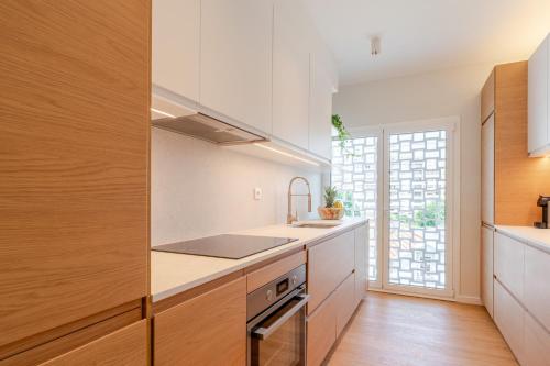 a kitchen with white cabinets and a sink and a window at Stylish & Spacious Apartment by HostWise in Porto
