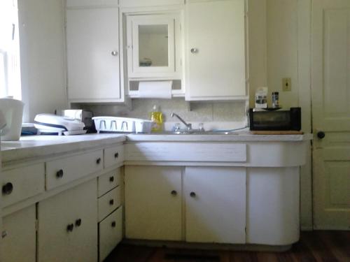 uma cozinha com armários brancos e um lavatório em Canora Vacation Home em Canora