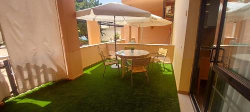 Un balcón con una mesa y sillas y una sombrilla. en Enebrales Home, en Punta Umbría