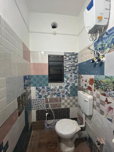 a bathroom with a toilet and a window in it at Maa Vaishno Inn in Lokpriya Gopinath Bordoloi International