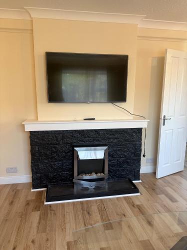 a living room with a fireplace with a tv above it at Cozy Kirkcaldy Hideaway - 3br House in Kirkcaldy