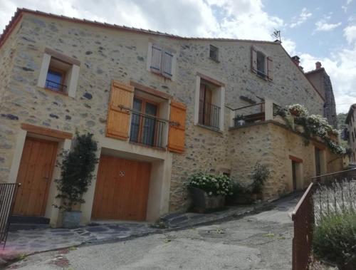 a large stone house with wooden doors and windows at Gite chez laetitia in CampÃ´me