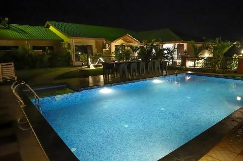a swimming pool at night with a table and chairs at Maitri Retreat in Panchgani