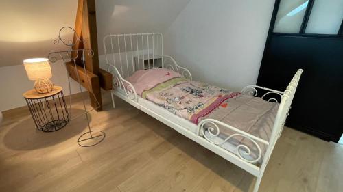 a small white bed in a room with a lamp at Au Gré des Souvenirs, gite 4 à 10 pers, clim, jacuzzi, loisirs in Château-la-Vallière