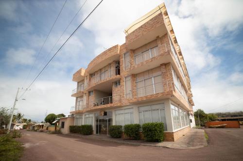 a tall brick building with windows on a street at Hotel Albatross in Puerto Ayora