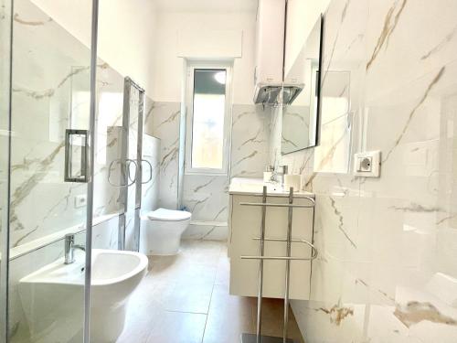 a white bathroom with a sink and a toilet at La casa di Mariposa in Sanremo