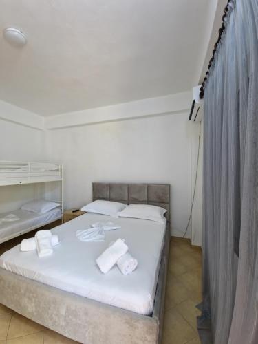 a bedroom with a bed with white sheets and towels at Villa Alvara in Vlorë