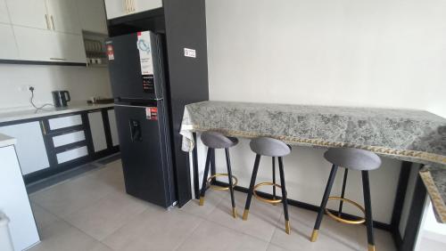 a kitchen with a counter and two stools under a table at Homestay Service Apartment Meta City Seri Kembangan-Putrajaya-Puchong-KL in Seri Kembangan