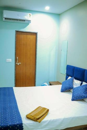 a bedroom with a bed with blue walls and a door at Hotel shiv ganga in Ujjain