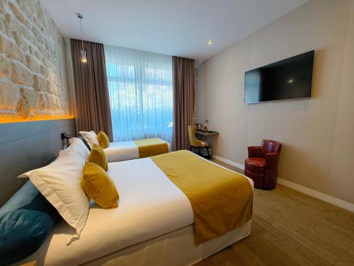 une chambre d'hôtel avec deux lits et une télévision à écran plat dans l'établissement Familia Hotel, à Paris