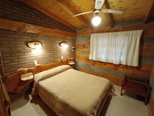 a bedroom with a bed in a log cabin at Cabañas Alvear in Huerta Grande