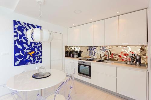 a kitchen with white cabinets and a white table and a table at Blue Bay Residence in Hvar