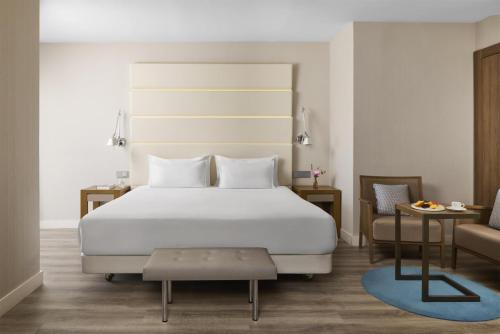 a bedroom with a large white bed and a chair at NH Madrid Balboa in Madrid