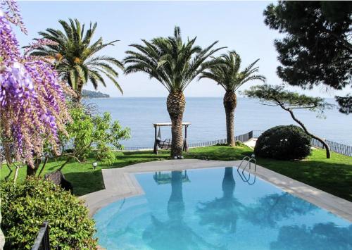 a swimming pool with palm trees and the ocean at Villa Büyükada I Private Pier & Seawater Pool in Istanbul