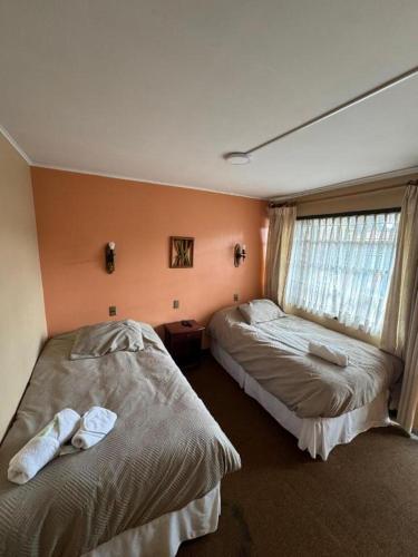 a bedroom with two beds and a window at Hotel Boutique WenuPillan in Villarrica