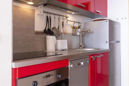 a kitchen with red cabinets and a white refrigerator at Résidence Le Borsat - Tignes Val Claret in Tignes