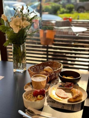 a table with breakfast foods and a vase with flowers at Hotel Boutique WenuPillan in Villarrica