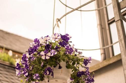 a white vase with purple flowers in it at Altstadt Suite in Weimar