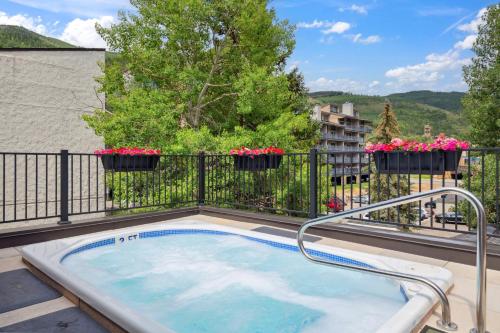 a hot tub on a balcony with flowers at Lift House Lodge, Pet Friendly, Premium Studio Condo in Vail
