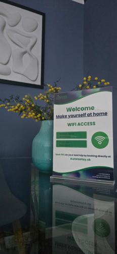 a sign sitting on a glass table with a vase at Modern And Cozy Apex Apartment in Helensburgh