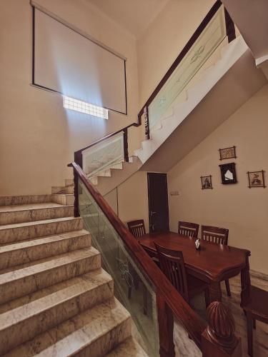 a dining room with a wooden table and stairs at Private Farm House in Moinabad with Tree house & Garden, pets allowed in Venkatāpur