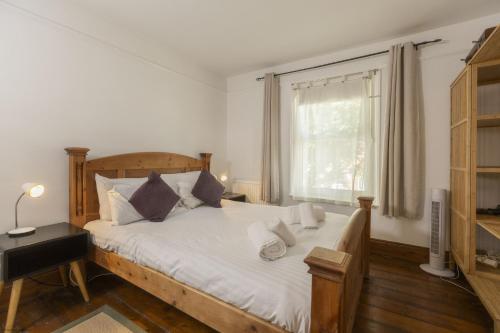 a bedroom with a bed with white sheets and a window at Orchard Cottage in Oxford