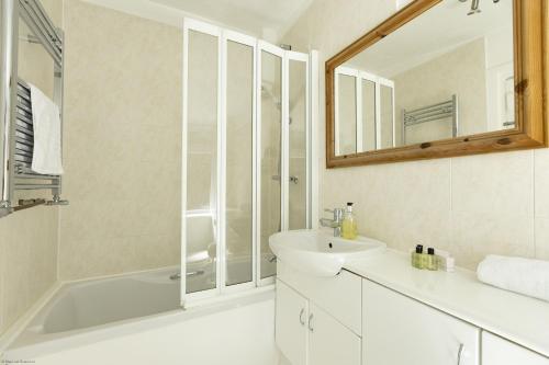 a bathroom with a tub and a sink and a mirror at Orchard Cottage in Oxford