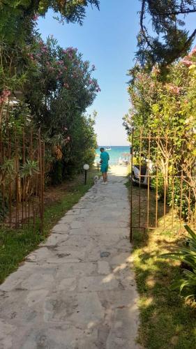 a man walking down a path next to the beach at Siviri summer studios in Siviri