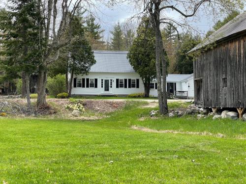 a large white house with a barn and trees at The ShackHilton at Dancing Light Farm in Bridgton