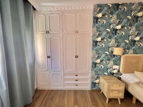 a bedroom with a large white cabinet with a floral wallpaper at Apartamento Centroplaya in Bueu