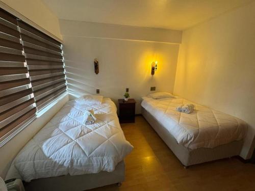 two twin beds in a bedroom with a window at Hotel Boutique WenuPillan in Villarrica